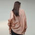 Person wearing a light pink satin blouse against a neutral background
